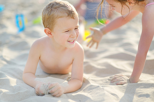 Two little kids having fun on a sandy beach