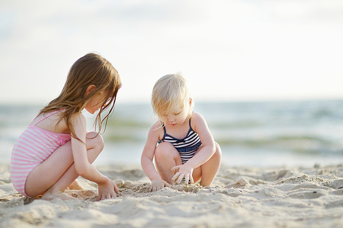Two little sisters having fun on a sandy beach