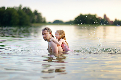 Little girl and her father having fun in a river at summer
