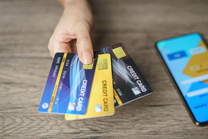 Woman hand showing her many credit card with smart phone for shopping online.