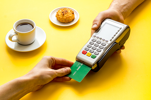 Payment by credit card. Hand hold card near terminal on table