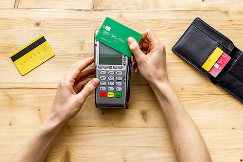 Payment by credit card. Hand hold card near terminal on desk top view