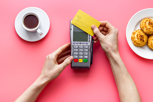 Payment transactions. Hand hold card near terminal on cafe table top-down