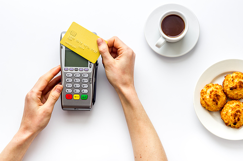 Payment transactions. Hand hold card near terminal on cafe table top-down