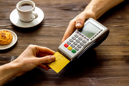 Payment transactions. Hand hold card near terminal on cafe table