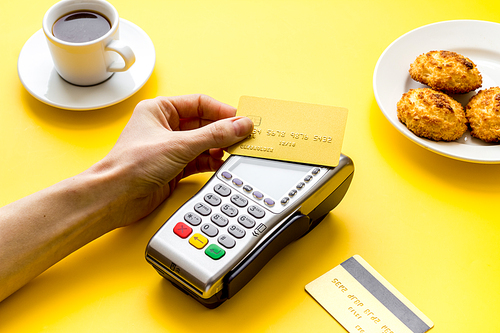 Payment by credit card. Hand hold card near terminal on table