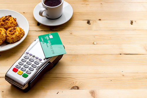 Payment transactions. Terminal and credit card on cafe wooden table.