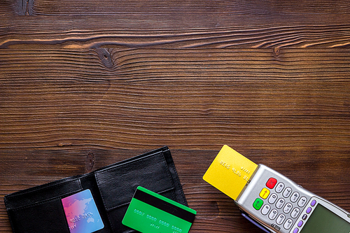 Payment by credit card. Terminal on wooden background top-down.