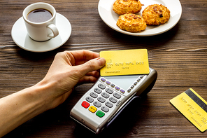 Payment transactions. Hand hold card near terminal on cafe table