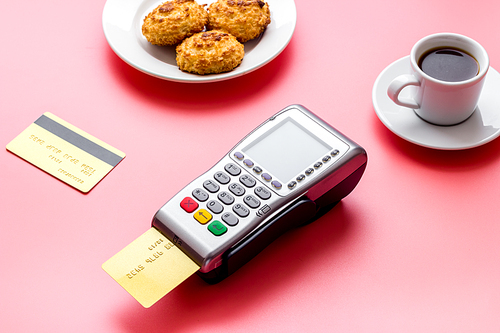 Payment transactions. Terminal and credit card on cafe pink table.