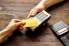 Payment by credit card. Hand hold card near terminal on table