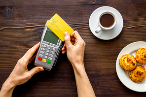 Payment transactions. Hand hold card near terminal on cafe table top-down