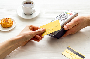 Payment transactions. Hand hold card near terminal on cafe table