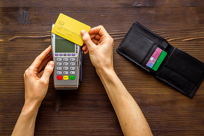 Payment by credit card. Hand hold card near terminal on desk top view