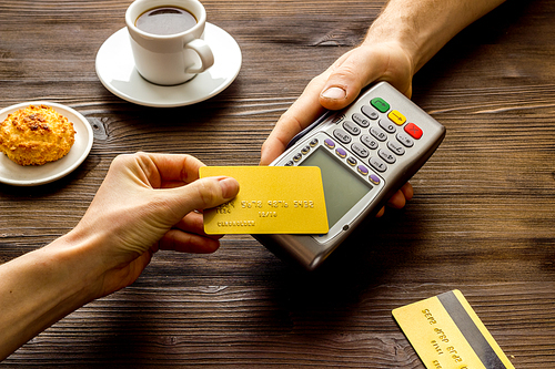 Payment transactions. Hand hold card near terminal on cafe table