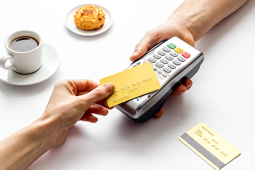 Payment transactions. Hand hold card near terminal on cafe table