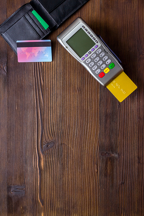 Payment by credit card. Terminal on wooden background top-down.