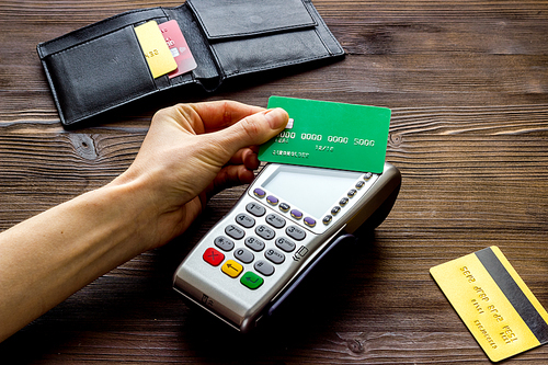 Payment by credit card. Hand hold card near terminal on table