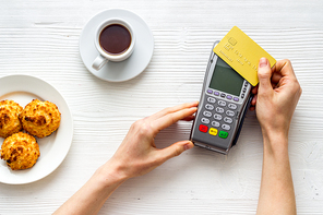 Payment transactions. Hand hold card near terminal on cafe table top-down