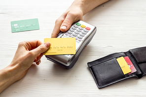 Payment by credit card. Hand hold card near terminal on table