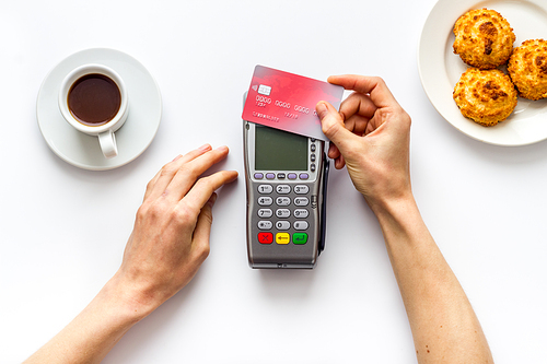 Payment transactions. Hand hold card near terminal on cafe table top-down