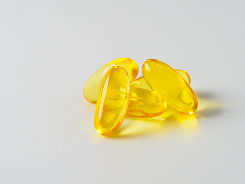 Omega 3 fish oil capsules isolated on white. Golden color capsules - vitamin E, D or multivitamin.