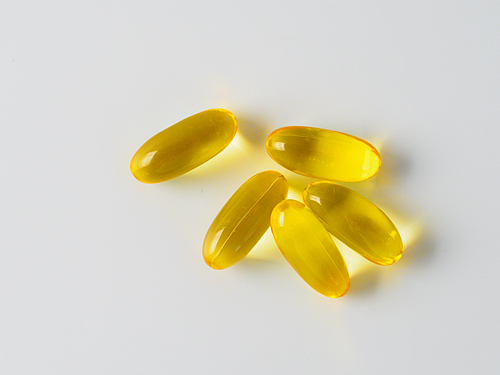 Omega 3 fish oil capsules isolated on white. Golden color capsules - vitamin E, D or multivitamin.