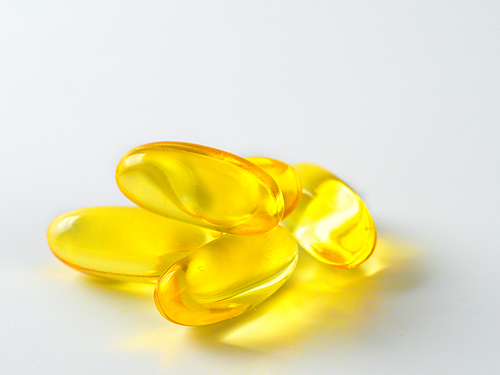 Omega 3 fish oil capsules isolated on white. Golden color capsules - vitamin E, D or multivitamin.