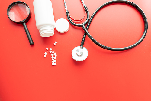 Medical, medicine stethoscope and pills on red background. Health care or illness. Tablet or drug in hospital or pharmacy. Cardiology heart treatment. Medication prescription