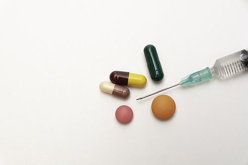 pharmaceuticals antibiotics pills, medicine pills, and capsules and syringe on white background.