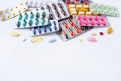 Various capsule medicines, pills and tablets in blister pack on white background.