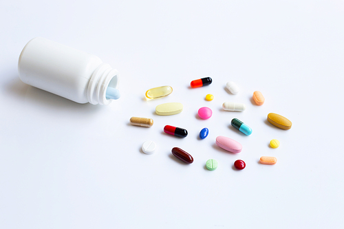 Colorful tablets with capsules and pills on white background.