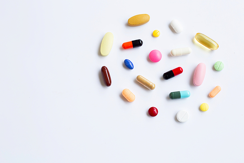 Colorful tablets with capsules and pills on white background.