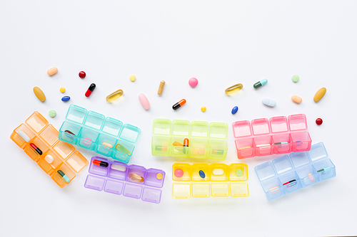 Many colored tablets and capsules  with pill box isolated on white