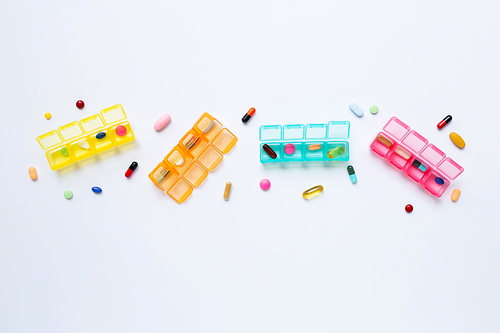 Many colored tablets and capsules  with pill box isolated on white. Copy space