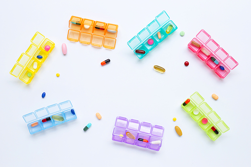 Many colored tablets and capsules  with pill box isolated on white. Copy space