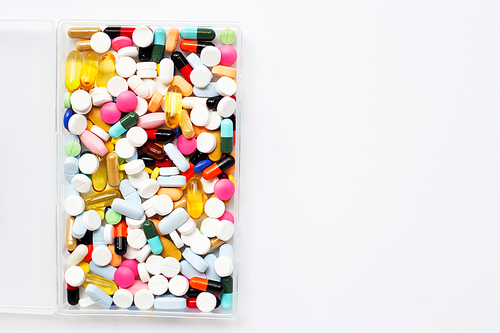 Colorful tablets with capsules and pills in plastic box on white background.