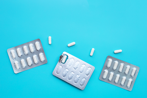 Capsule medicines in blister pack on blue background. Copy space