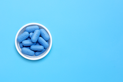 PrEP ( Pre-Exposure Prophylaxis) used to prevent HIV, on plastic pill bottle cap. Blue background, Copy space