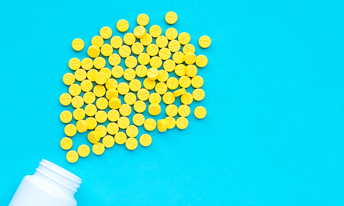 Yellow tablets of Paracetamol on blue background.