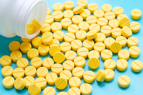 Yellow tablets of Paracetamol on blue background.