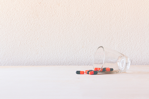 Pill in glass on wooden floor and concrete background