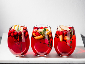 Winter sangria on tabletop. Three glasses of sangria with fruit slice, cranberry and rosemary. Copy space top for text or design.