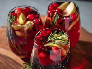 Winter sangria on tabletop. Three glasses of sangria with fruit slice, cranberry and rosemary
