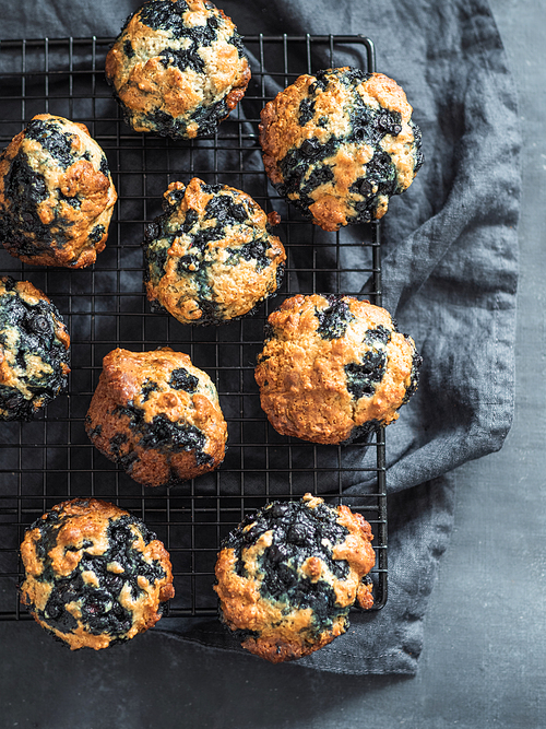 Homemade vegan blueberry muffins on dark background. Vertical. Top view or flat lay.