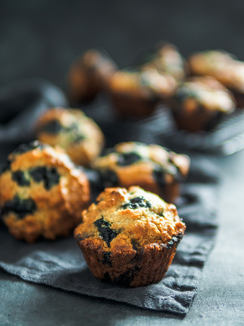 Homemade vegan blueberry muffins on dark background. Copy space for text or design. Low key. Vertical.