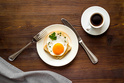 Fried eggs sandwich on plate - dark wooden table top view.