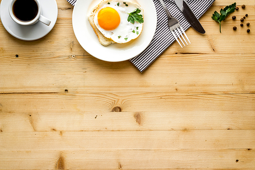 Fried eggs sandwich on plate - light wooden background top-down.