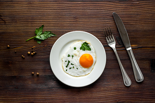 Fried eggs on plate - dark wooden table top view.