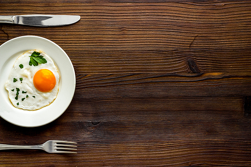 Fried eggs on plate - dark wooden dinner table from above.